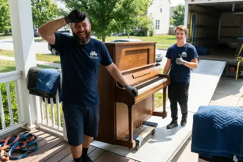 Piano buiten op veranda klaar voor verhuizing met verhuiswagen op achtergrond